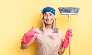 Orta yaşlı, güzel bir kadın kendini mutlu hissediyor ve heyecanla kendini işaret ediyor. ev ve süpürge kavramı