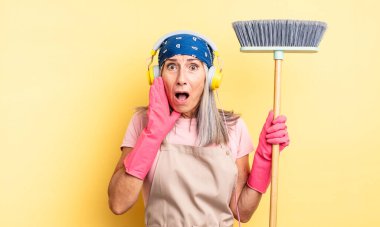 Orta yaşlı, güzel bir kadın şok olmuş ve korkmuş hissediyor. ev ve süpürge kavramı