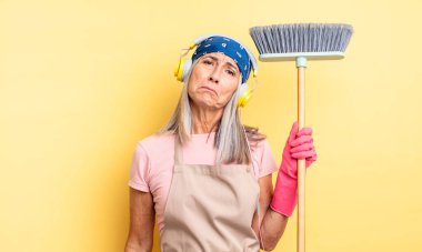 Orta yaşlı, güzel bir kadın üzgün ve mızmızlanıyor. Mutsuz bir bakışı var ve ağlıyor. ev ve süpürge kavramı