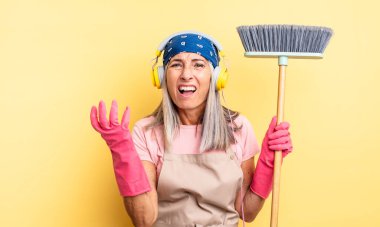 Orta yaşlı, güzel bir kadın umutsuz, sinirli ve stresli görünüyor. ev ve süpürge kavramı