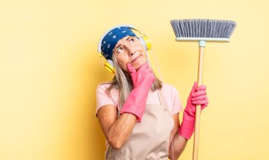 Orta yaşlı, düşünceli, kuşkulu ve kafası karışık bir kadın. ev ve süpürge kavramı