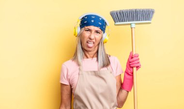 Orta yaşlı, güzel bir kadın iğreniyor, sinirleniyor ve dili dışarı çıkıyor. ev ve süpürge kavramı