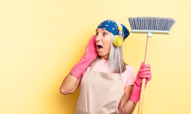 Orta yaşlı, güzel bir kadın mutlu, heyecanlı ve şaşırmış hissediyor. ev ve süpürge kavramı