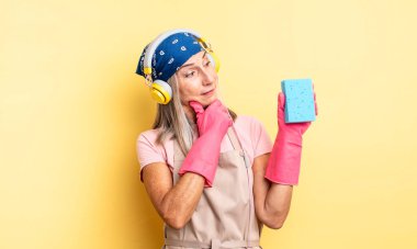 Orta yaşlı güzel bir kadın mutlu, kendinden emin ve elleri çenesinde gülümsüyor. Temizleyici.