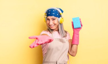 Orta yaşlı, güzel bir kadın arkadaşça gülümsüyor ve bir konsept sunuyor. Temizleyici.