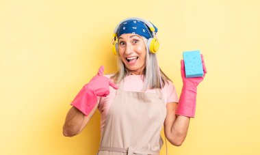 Orta yaşlı, güzel bir kadın kendini mutlu hissediyor ve heyecanla kendini işaret ediyor. Temizleyici.