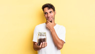 Mutlu, kendine güvenen, elleri çenesinde gülümseyen İspanyol yakışıklı bir adam. Kahve şişesi.