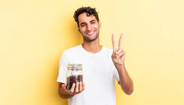 İspanyol yakışıklı adam gülümsüyor ve mutlu görünüyor, zafer ya da barış işareti yapıyor. Kahve şişesi.