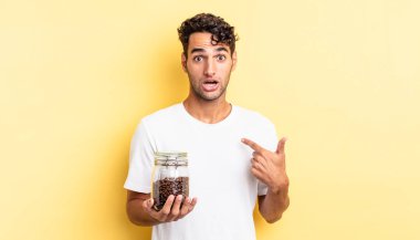 İspanyol yakışıklı adam mutlu hissediyor ve heyecanla kendini işaret ediyor. Kahve şişesi.