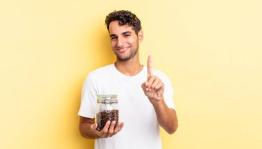 Hispanik yakışıklı adam gururla gülümsüyor ve kendinden emin bir numara oluyor. Kahve şişesi.