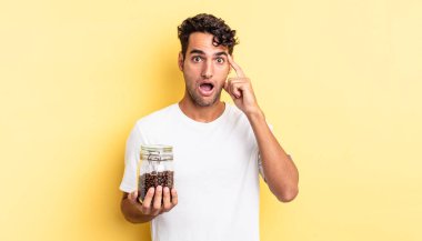 İspanyol yakışıklı adam şaşırmış görünüyor, yeni bir düşünce, fikir ya da konsept fark ediyor. Kahve şişesi.