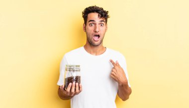 İspanyol yakışıklı adam şok olmuş ve ağzı açık, kendini işaret ederek şaşırmış görünüyor. Kahve şişesi.