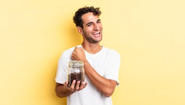 İspanyol yakışıklı adam kendini mutlu hissediyor ve bir meydan okumayla yüzleşiyor ya da kutluyor. Kahve şişesi.