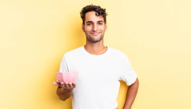 İspanyol yakışıklı adam mutlu bir şekilde gülümsüyor, eli kalçasında ve kendinden emin. Kahve şişesi. boş kase kavramı