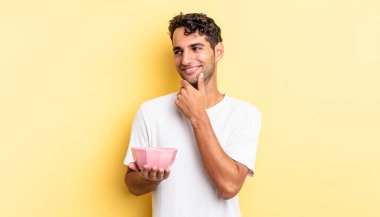 Mutlu, kendine güvenen, elleri çenesinde gülümseyen İspanyol yakışıklı bir adam. boş kase kavramı