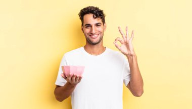 İspanyol yakışıklı adam kendini mutlu hissediyor, iyi bir jestle onaylıyor. boş kase kavramı