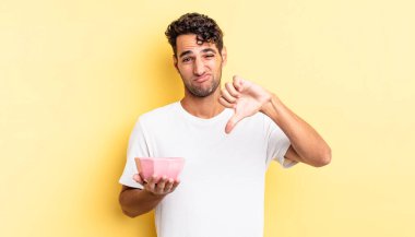 Latin asıllı yakışıklı adam kızgın, baş parmağını kaldırıyor. boş kase kavramı