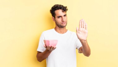 İspanyol yakışıklı adam ciddi görünüyor. Avuç içi gösteriyor. Durdurma hareketi yapıyor. boş kase kavramı