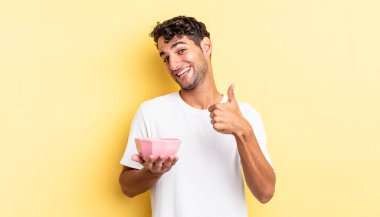 İspanyol yakışıklı adam kendini gururlu hissediyor, başparmağıyla olumlu gülümsüyor. boş kase kavramı