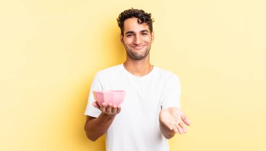 İspanyol yakışıklı adam mutlu bir şekilde gülümsüyor ve bir konsept sunuyor. boş kase kavramı