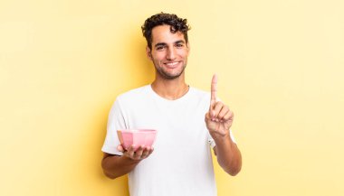 Hispanik yakışıklı adam gururla gülümsüyor ve kendinden emin bir numara oluyor. boş kase kavramı