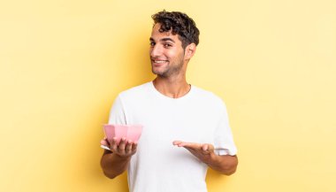 İspanyol yakışıklı adam neşeyle gülümsüyor, mutlu hissediyor ve bir konsept gösteriyor. boş kase kavramı