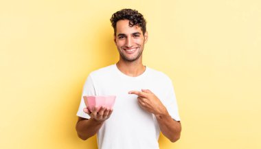 İspanyol yakışıklı adam neşeyle gülümsüyor, mutlu hissediyor ve bir tarafı işaret ediyor. boş kase kavramı