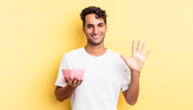 İspanyol yakışıklı adam gülümsüyor ve arkadaş canlısı görünüyor, beş numarayı gösteriyor. boş kase kavramı