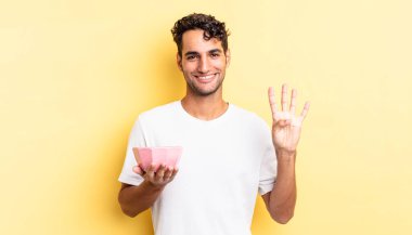 İspanyol yakışıklı adam gülümsüyor ve arkadaş canlısı görünüyor, dört numarayı gösteriyor. boş kase kavramı