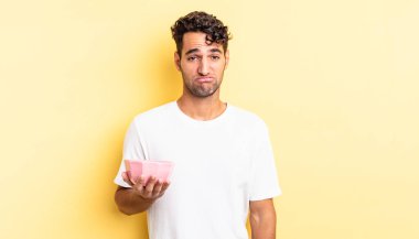 Hispanik yakışıklı adam üzgün ve mızmız, mutsuz bir bakışla ağlıyor. boş kase kavramı