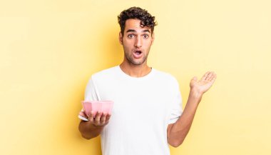 İspanyol yakışıklı adam şaşırmış ve şok olmuş görünüyor. Çenesi düşmüş ve elinde bir nesne var. boş kase kavramı