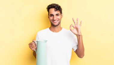 İspanyol yakışıklı adam kendini mutlu hissediyor, iyi bir jestle onaylıyor. Kahve termosu kavramı