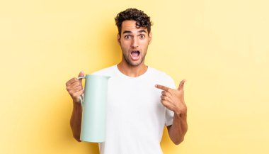 İspanyol yakışıklı adam mutlu hissediyor ve heyecanla kendini işaret ediyor. Kahve termosu kavramı