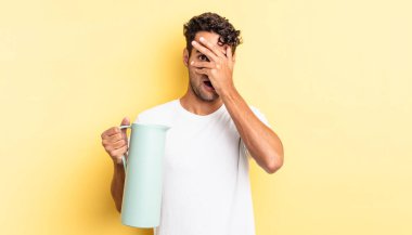 İspanyol yakışıklı adam şok olmuş, korkmuş ya da korkmuş görünüyor. Yüzü elle kapatılmış. Kahve termosu kavramı