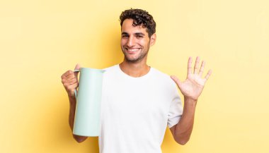 İspanyol yakışıklı adam gülümsüyor ve arkadaş canlısı görünüyor, beş numarayı gösteriyor. Kahve termosu kavramı