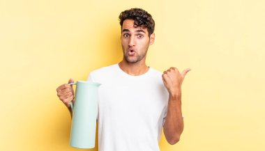 İspanyol yakışıklı adam, inançsızlıktan şaşkın şaşkın bakıyor. Kahve termosu kavramı