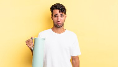 Hispanik yakışıklı adam üzgün ve mızmız, mutsuz bir bakışla ağlıyor. Kahve termosu kavramı