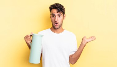 İspanyol yakışıklı adam şaşırmış ve şok olmuş görünüyor. Çenesi düşmüş ve elinde bir nesne var. Kahve termosu kavramı