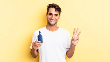 İspanyol yakışıklı adam gülümsüyor ve arkadaş canlısı görünüyor, üç numarayı gösteriyor. buharlaştırıcı kavramı