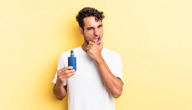 Ağzı ve gözleri açık, eli çenesinde İspanyol yakışıklı bir adam. buharlaştırıcı kavramı