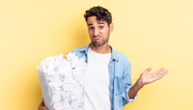 İspanyol yakışıklı adam şaşkın, şaşkın ve şüpheci hissediyor. kağıt toplar çöp konsepti