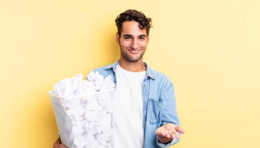 İspanyol yakışıklı adam mutlu bir şekilde gülümsüyor ve bir konsept sunuyor. kağıt toplar çöp konsepti