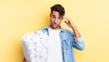 İspanyol yakışıklı adam mutlu, şaşkın ve şaşırmış görünüyor. kağıt toplar çöp konsepti