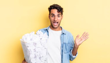 İspanyol yakışıklı adam kendini mutlu hissediyor ve inanılmaz bir şeye hayret ediyor. kağıt toplar çöp konsepti