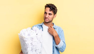 İspanyol yakışıklı adam stresli, endişeli, yorgun ve hayal kırıklığına uğramış hissediyor. kağıt toplar çöp konsepti