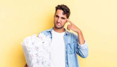 İspanyol yakışıklı adam kafası karışık ve şaşkın hissediyor, senin deli olduğunu gösteriyor. kağıt toplar çöp konsepti