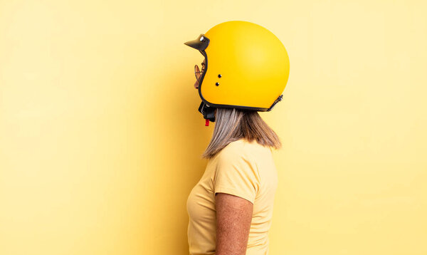 middle age pretty woman on profile view thinking, imagining or daydreaming. motorbike helmet concept