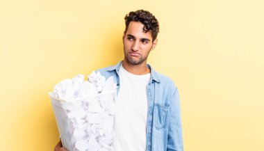 Hispanik yakışıklı adam üzgün, üzgün ya da kızgın hissediyor ve yana bakıyor. kağıt toplar çöp konsepti