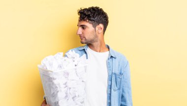 Profil görünümlü İspanyol yakışıklı adam hayal mi kuruyor, hayal mi kuruyor, hayal mi kuruyor? kağıt toplar çöp konsepti