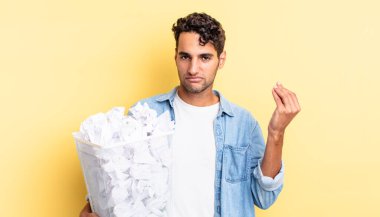 İspanyol yakışıklı adam kapiş ya da para hareketi yapıyor, sana ödemeni söylüyor. kağıt toplar çöp konsepti